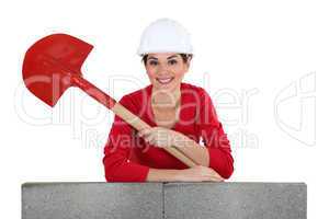 Girl with shovel leaning on a brickwall