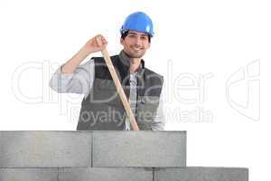 Man holding hammer by unfinished wall