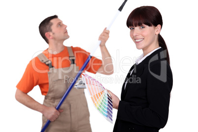 Interior decorator holding colour samples while a man paints
