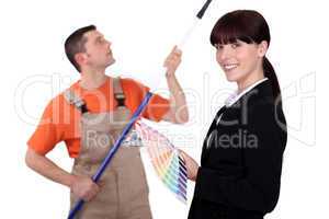Interior decorator holding colour samples while a man paints
