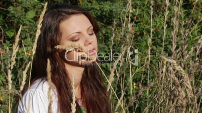 Beautiful girl sits in a high grass