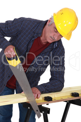 Construction worker sawing a plank of wood