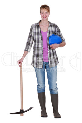 Woman construction worker standing with a pickaxe