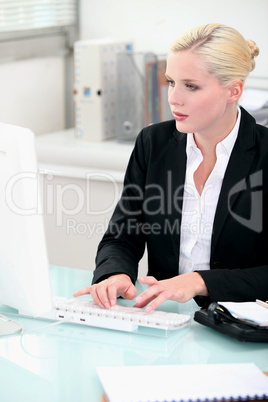 Blonde woman working at a desktop computer