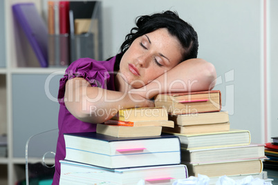Overworked woman sleeping on a stack of books