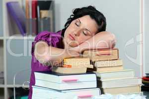 Overworked woman sleeping on a stack of books