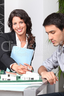 Female architect showing model to man