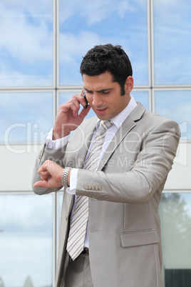 Businessman talking on a cell and checking his watch