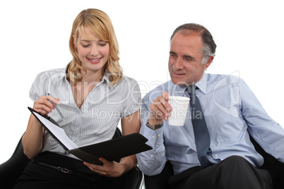 businessman drinking coffee and talking to his assistant
