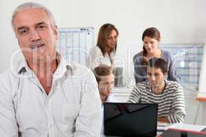 55 years old man watching us and  four young people focused on a laptop