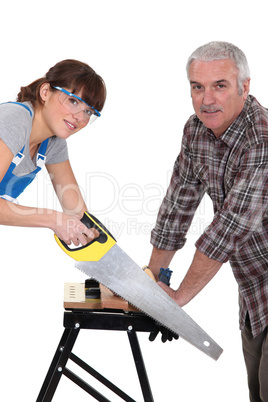 Father and daughter sawing plank of wood