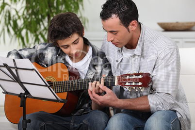 Father teaching son the guitar