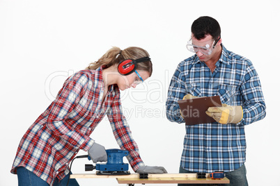 Man evaluating a tradeswoman on her use of a jigsaw