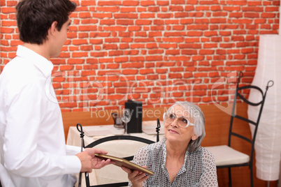 Man handing menu to old lady