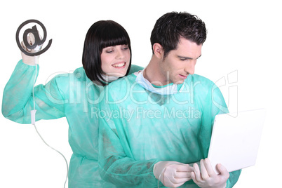 Medical staff using laptop and drip with at sign