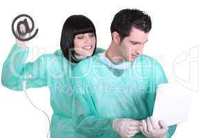 Medical staff using laptop and drip with at sign