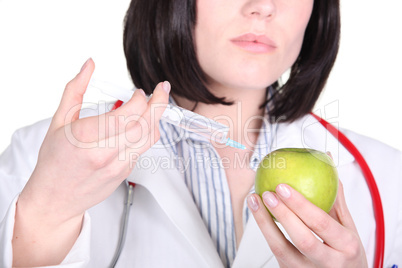 Doctor injecting hormone drugs into an apple