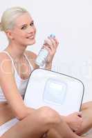 Woman with a bottle of water and electronic scales