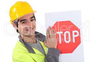 road worker hiding the letter s of a stop sign