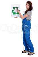 A female manual worker holding a recycle sign.