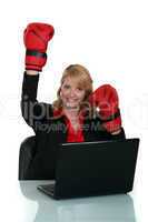 Woman wearing boxing gloves whilst sat at desk