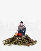 Man sitting on a toolbox and pile of giant screws