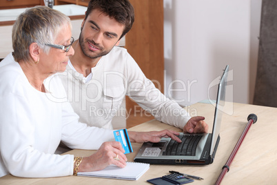 Young man helping senior woman buy online