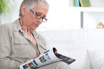 Elderly woman reading magazine
