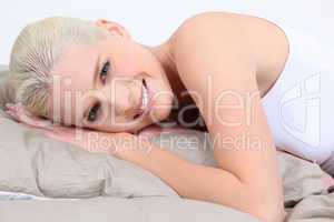 Smiling young woman lying in bed