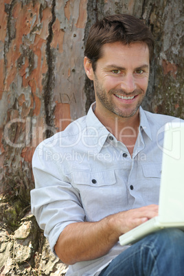 Man with laptop under tree