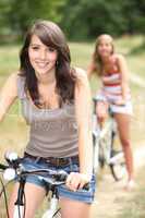 Two girls riding bikes through the forest