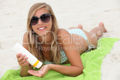 Young woman using sun cream on the beach