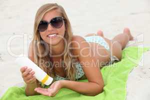 Young woman using sun cream on the beach