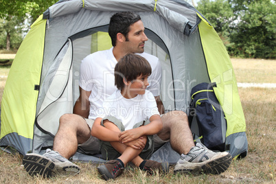 Father and son sitting outside a tent