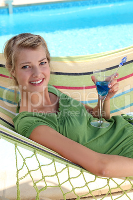 a woman drinking a cocktail near a swimming-pool