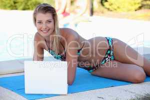 Young blonde at poolside with computer