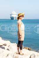 Woman with hat standing at sea