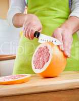 Woman's hands cutting grapefruit