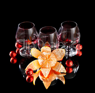 Glasses of wine, tangerine and chocolate on a black background