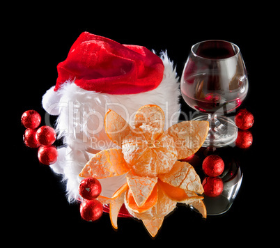 Glasses of wine, tangerine and chocolate and Santa Claus hat on a black background