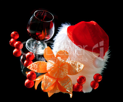 Glasses of wine, tangerine and chocolate and Santa Claus hat on a black background