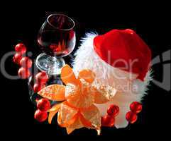 Glasses of wine, tangerine and chocolate and Santa Claus hat on a black background