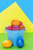 Easter eggs in a bucket on a colored background