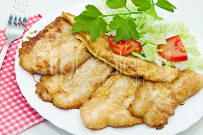 Fried fish fillets with egg and salad.