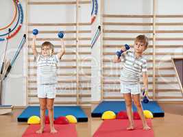 A boy with a dumbbell in the gym.