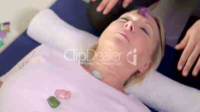 Young therapist arranging crystals on female client for reiki therapy