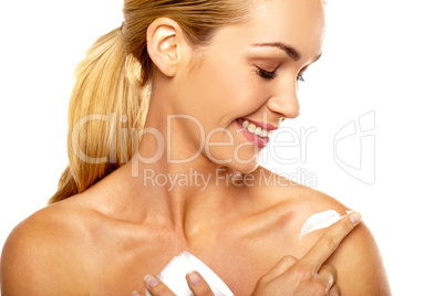Smiling woman applying body cream