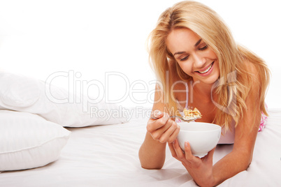 Woman eating cereal in bed