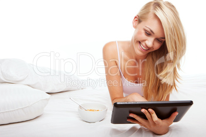 Beautiful blonde using a tablet in bed