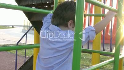 Little boy climbing bars at park